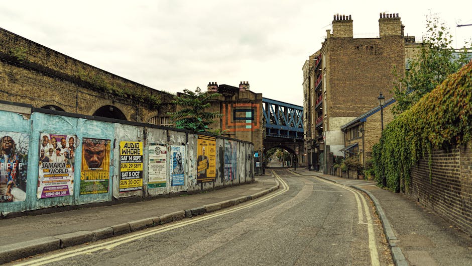 A quiet residential street in Dalston Kingsland featuring Victorian terraced houses with bay windows, decorative brickwork, and white-painted facades. The pavement on the right side is lined with a bl